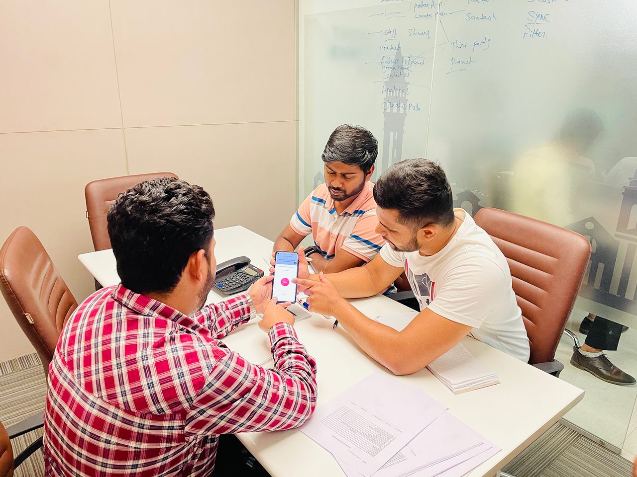 A closer moment from the same session: the participant holds a Pataa screen while a teammate points something out.